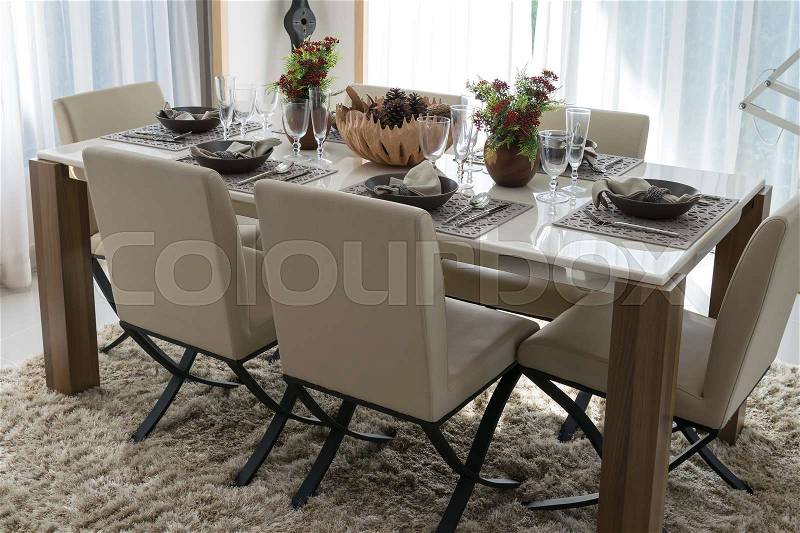 Dining table and comfortable chairs in modern home with elegant table setting, stock photo