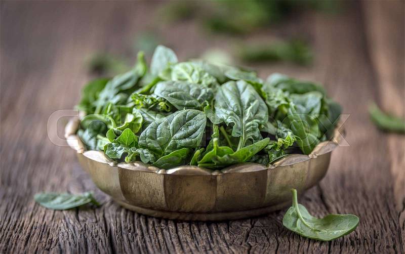 Spinach leaves.Fresh spinach leaves in retro bowl on oak wood board. Selective focus, stock photo