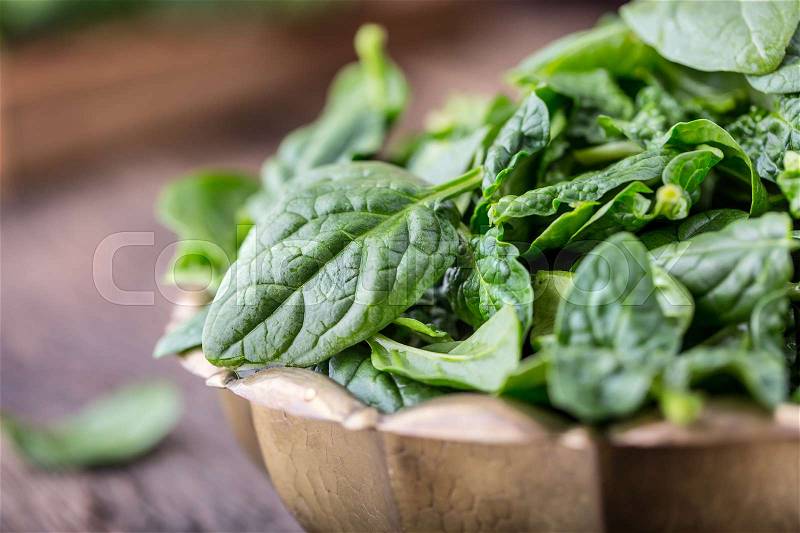 Spinach leaves.Fresh spinach leaves in retro bowl on oak wood board. Selective focus, stock photo