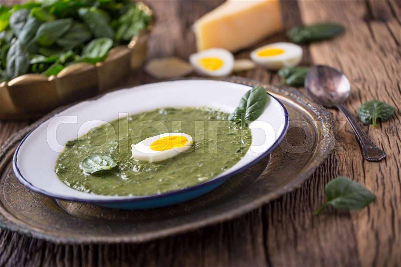 Spinach soup. Portion spinach soup with egg and cheese parmesan in retro style, stock photo