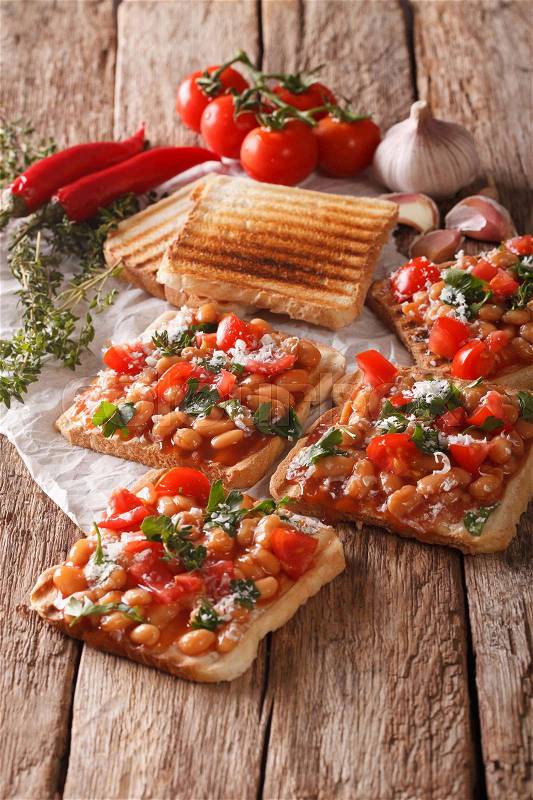 English cuisine: toast with white beans, tomatoes, cheese and garlic close-up on the table. vertical , stock photo