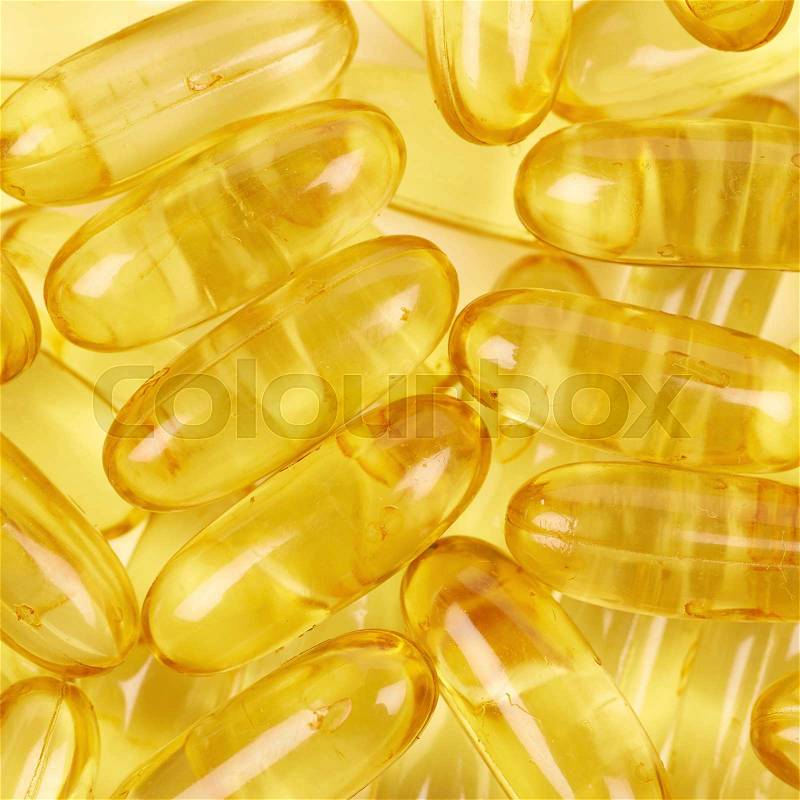 Surface covered with multiple yellow softgel pills as a medical backdrop composition, stock photo