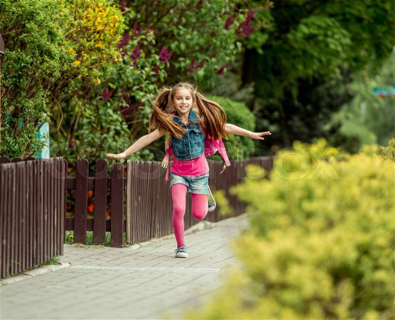 Little girl with a backpack run from school, stock photo