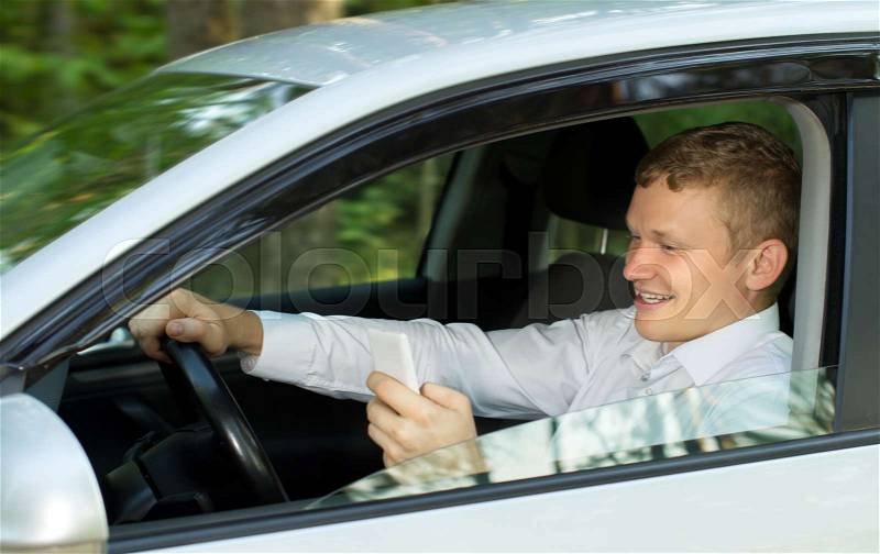 Young man talking on the phone behind the wheel of a car, creating an emergency situation, stock photo