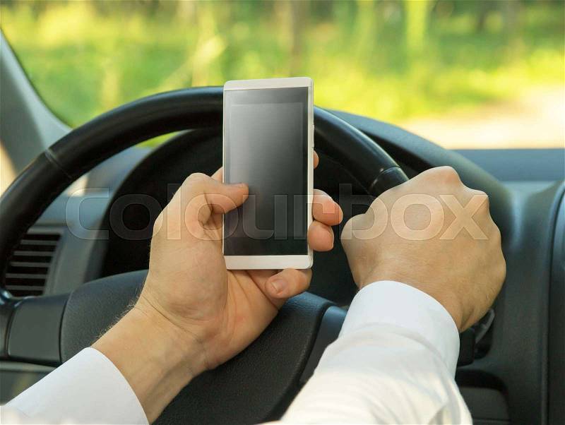 Young man uses a mobile phone, driving a car. Breaking the rules, stock photo