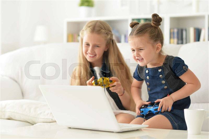 Portrait of a cute little sisters play video game, stock photo