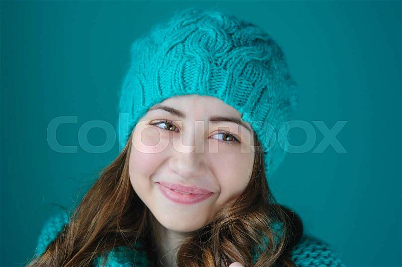 Beautiful young woman in a turquoise knitted hat posing in studio, stock photo