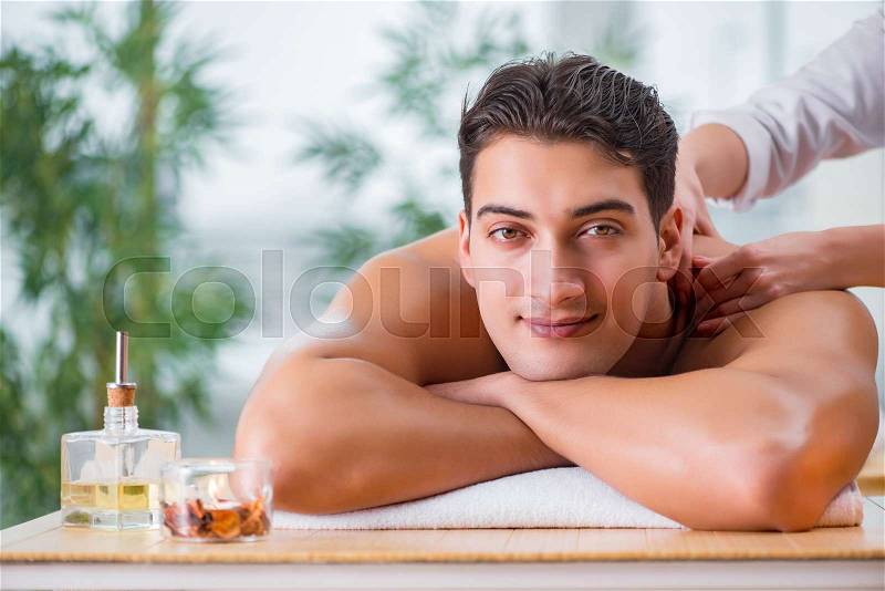 Handsome man during spa massaging session, stock photo