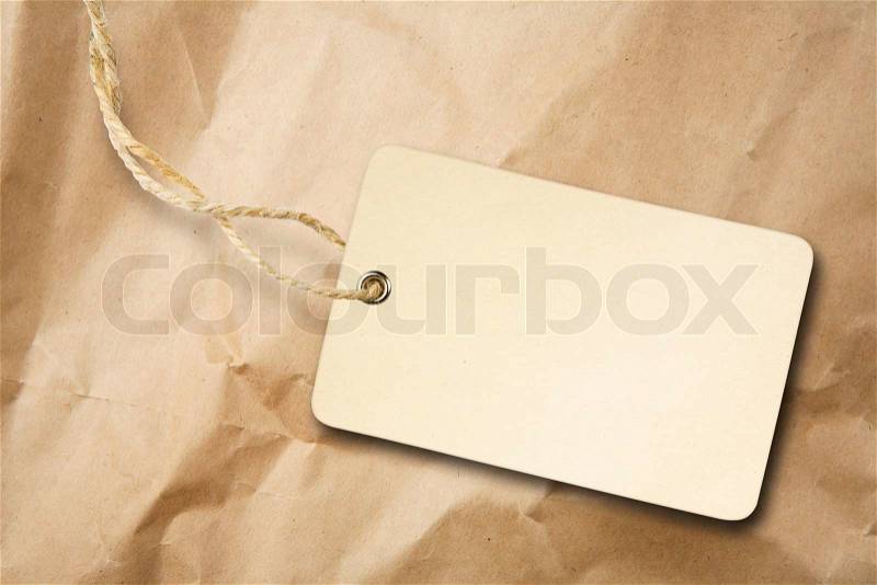Blank packaging label with cotton string on crumpled brown paper, stock photo