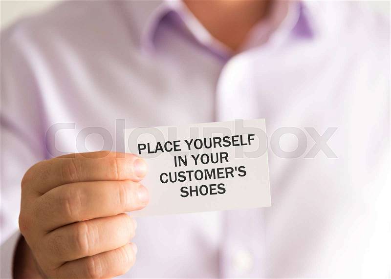 Closeup on businessman holding a card with text PLACE YOURSELF IN YOUR CUSTOMERS SHOES, business concept image with soft focus background, stock photo