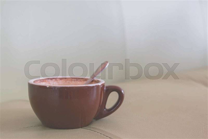 Brown cup of coffee on soft green sofa in the coffee shop. Coffee cup relaxation concept, stock photo