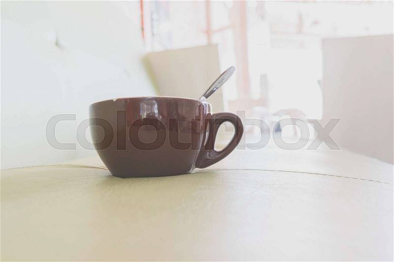 Brown cup of coffee on soft green sofa in the coffee shop. Coffee cup relaxation concept, stock photo