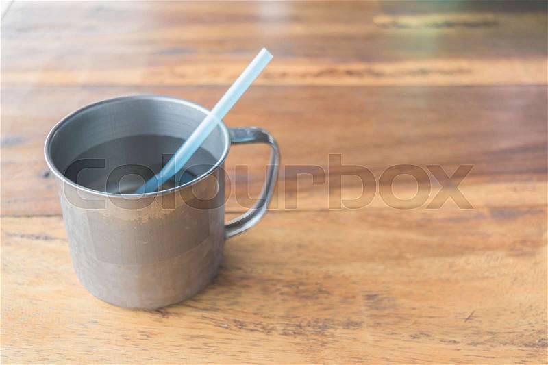 Cup of water with blue straw on the wood table, stock photo