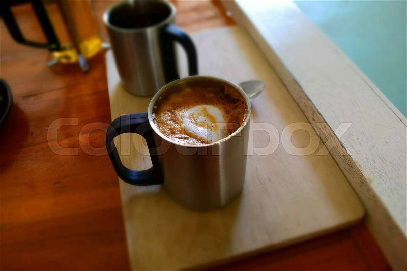 Hot dark coffee in stainless cup with cup of hot tea and stainless spoon on the wood. Dark coffee concept, stock photo
