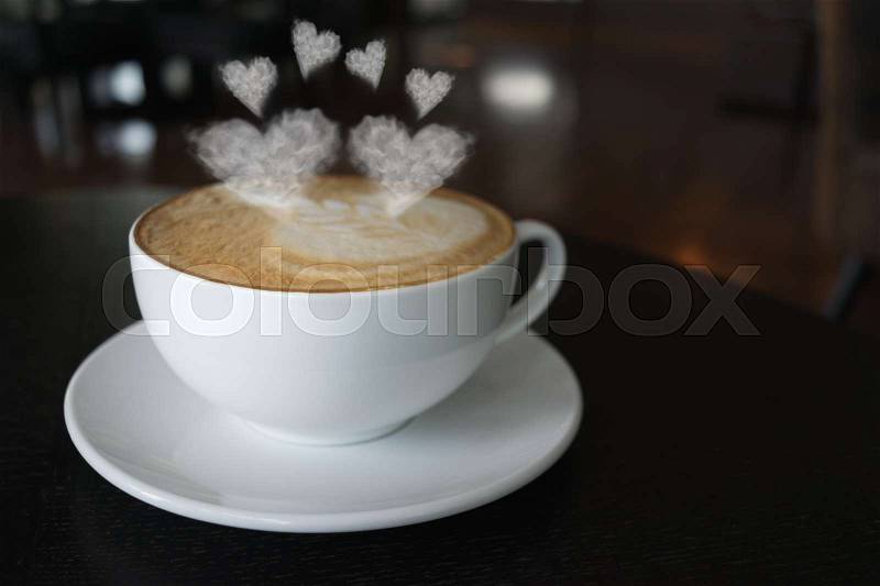 Coffee cup on the table at the coffee shop with heart shaped smoke vintage color tone, stock photo