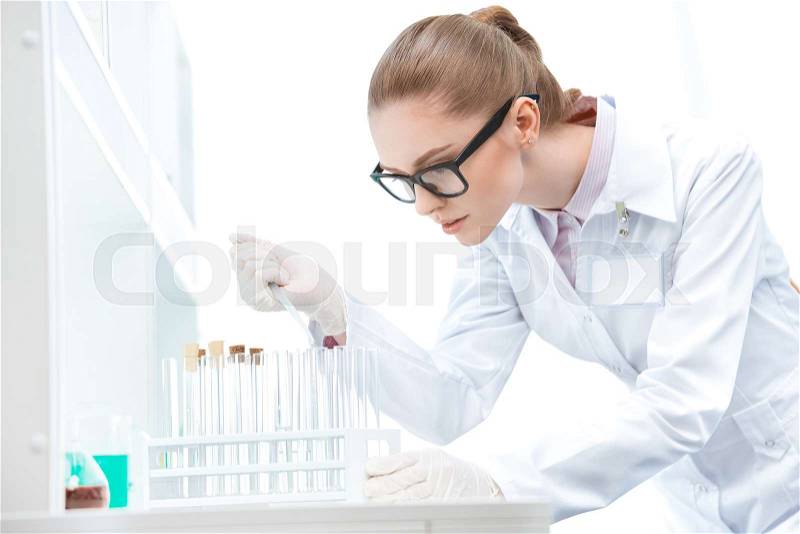 Young concentrated woman scientist in eyeglasses working with test tubes and pipette , stock photo
