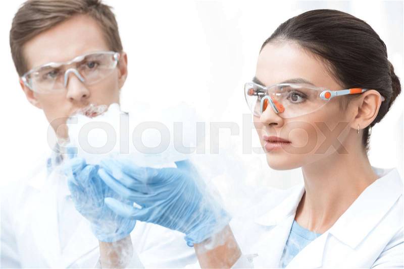Young professional chemists in protective glasses making experiment with liquid nitrogen , stock photo