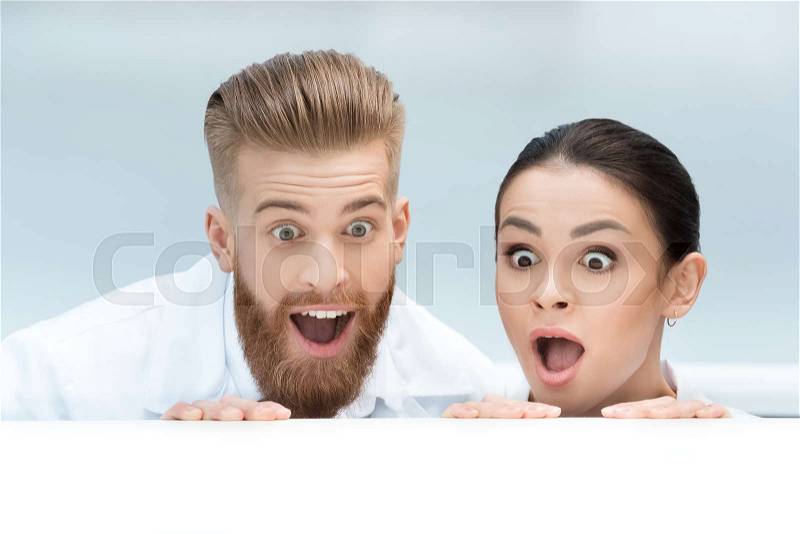 Portrait of surprised scientists looking out behind table in lab, stock photo
