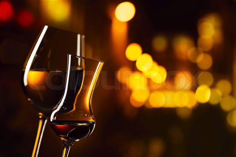 Closeup of glasses with white wine and liquor on a background of night city, stock photo