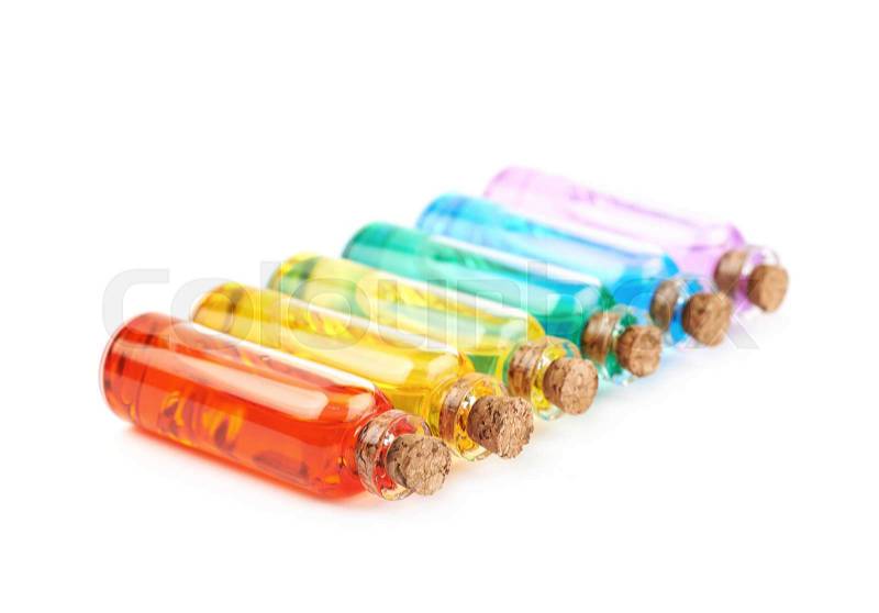 Set of multiple tiny glass vial bottles filled with the rainbow colored liquids, composition isolated over the white background, stock photo