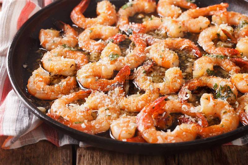 Shrimp with garlic, parmesan and herbs closeup on a frying pan. Horizontal , stock photo