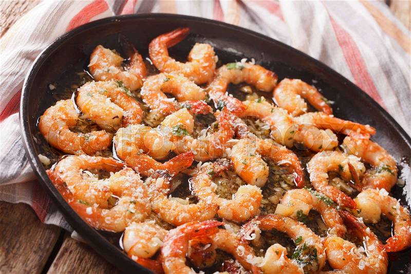 Fried shrimp in garlic sauce with parmesan cheese and herbs in a pan close-up. horizontal , stock photo