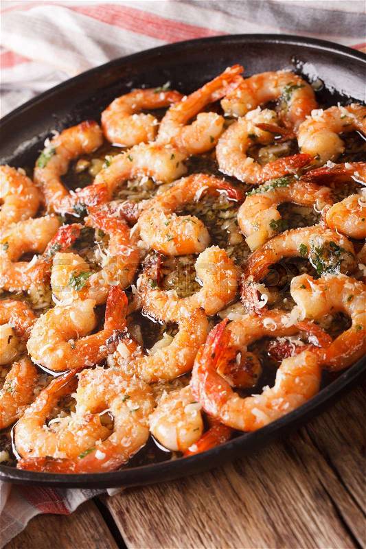 Fried shrimp in garlic sauce with parmesan and herbs closeup on a frying pan. vertical , stock photo