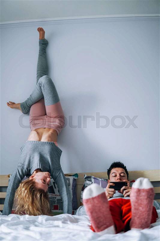 Man and woman on the bed, girl standing on hands upside down, stock photo
