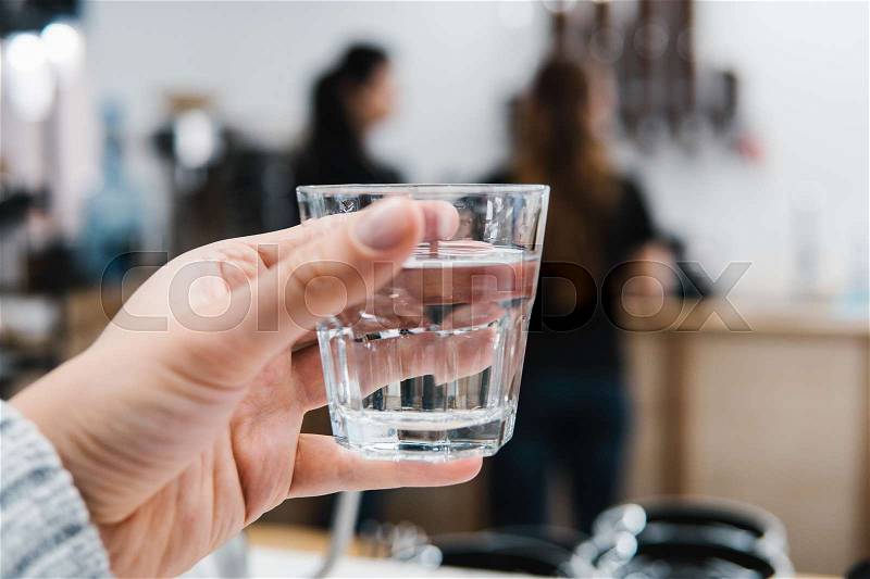 Glass of water in hand on a light background, stock photo