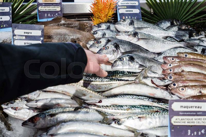 Woman customer hand point at fish stall fish counter to the fresh Gilt-head bream fish daurade , stock photo