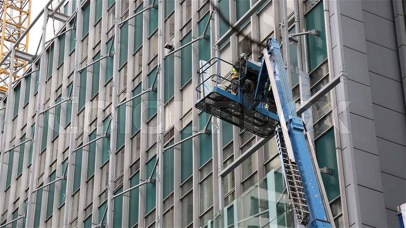 Worker hydraulic crane installing windows, stock photo