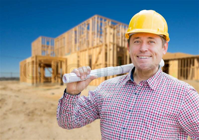 Smiling Contractor Wearing Hardhat Holding Blueprints at Home Construction Site, stock photo