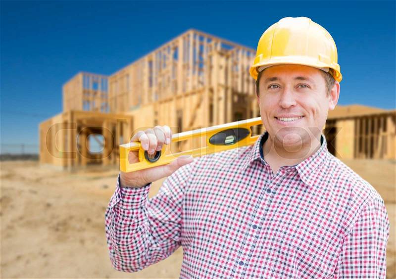 Smiling Male Contractor in Hardhat Holding Blueprints and Level at Home Construction Site, stock photo