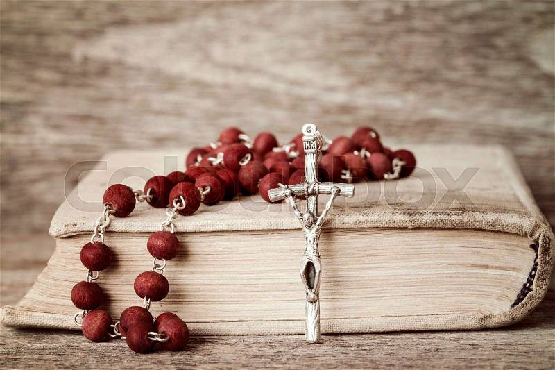 Close-up of prayer book and rosary on wooden background, stock photo