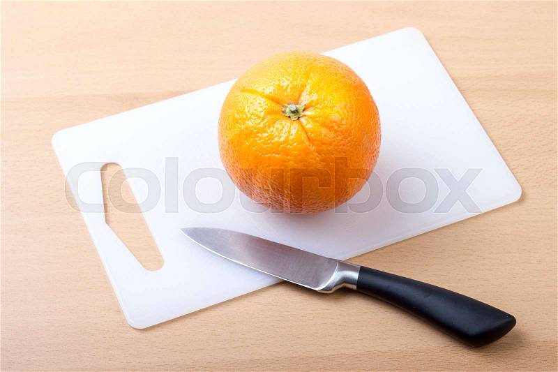 Orange on white cutting board with knife - horizontal image, stock photo