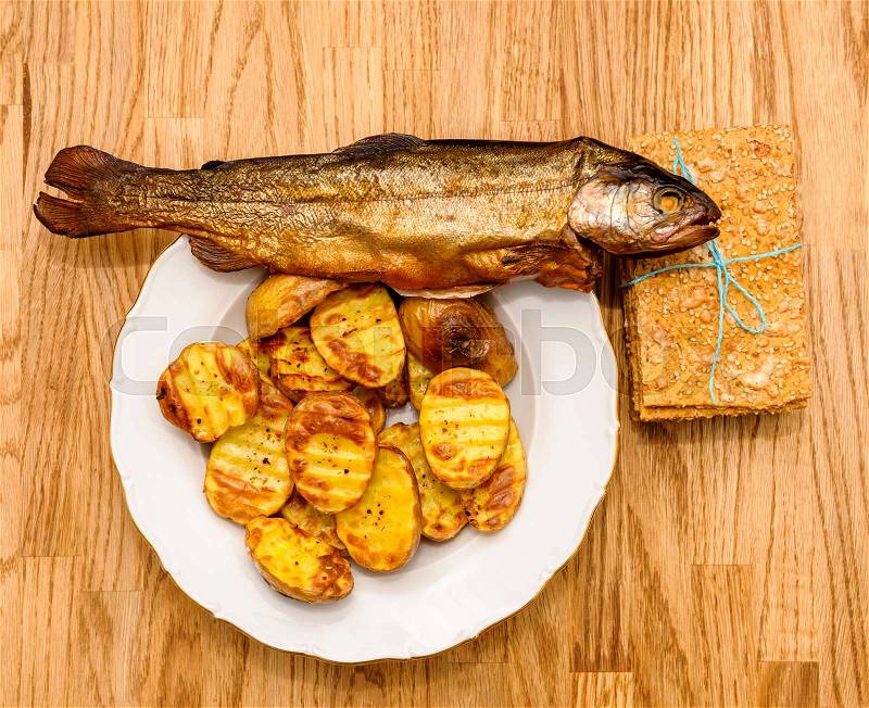 Delicious crispbread tied with organic blue thread on wooden oak table next to smoked fish and baked patatoes, stock photo