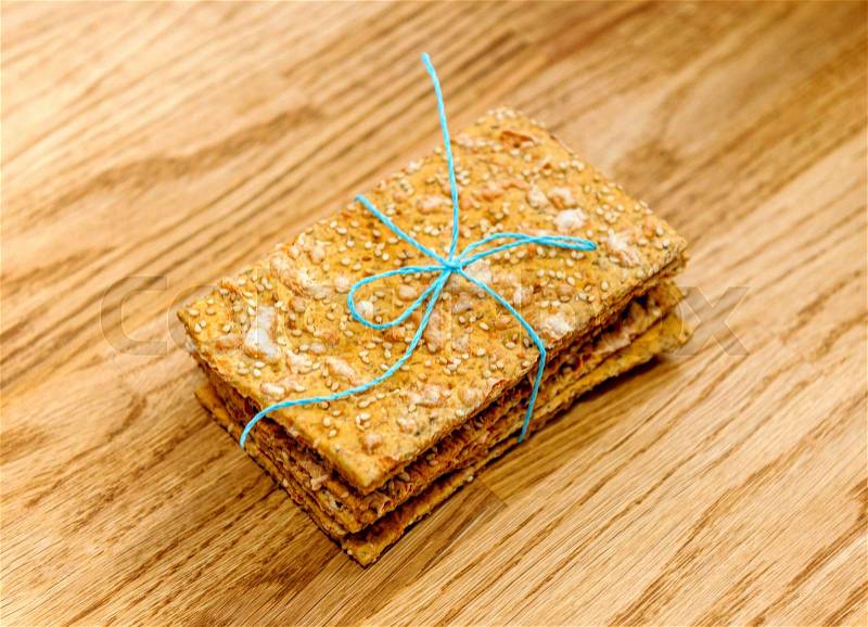 Delicious crispbread tied with organic blue thread on wooden oak table , stock photo