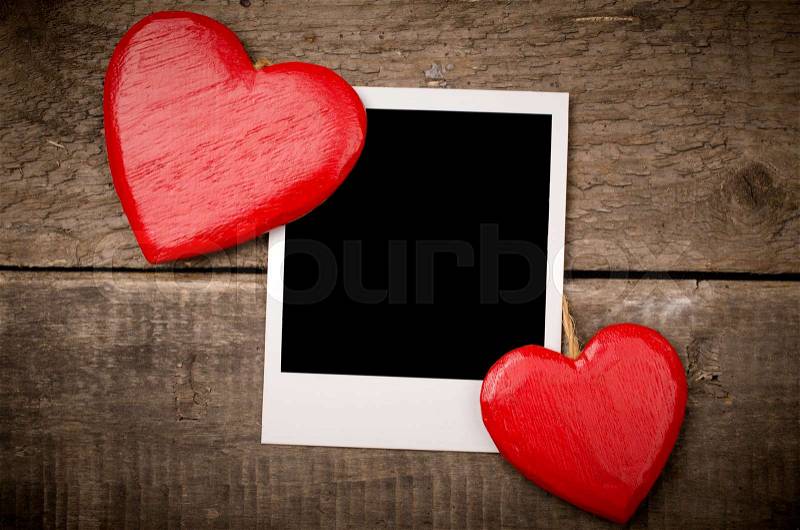 Two red wooden heart shapes with an old photograph, stock photo