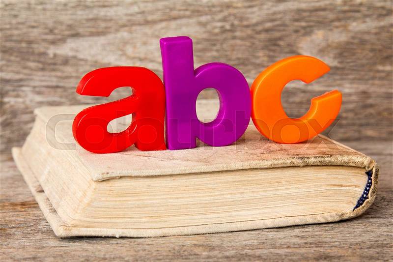 ABC spelling and old book on wooden background, stock photo