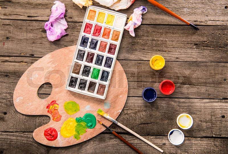 Top view of paints, paintbrushes and palette on table, stock photo