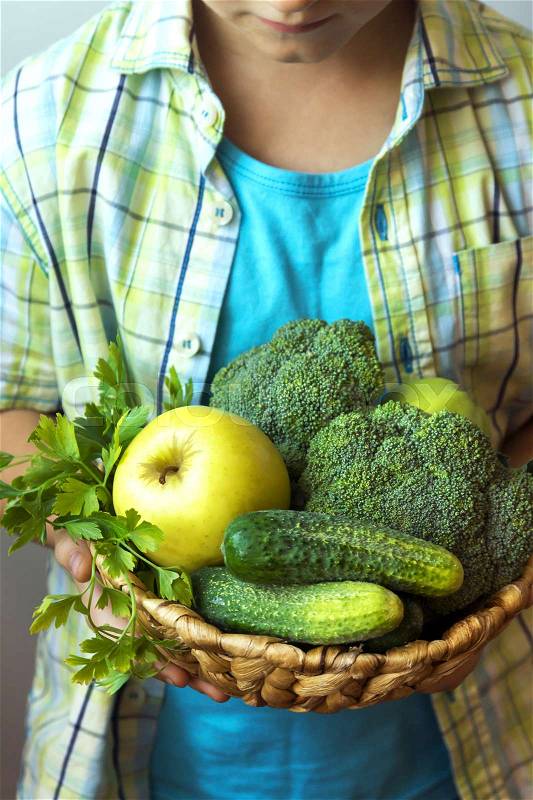 Person (hands) hold basket with organic green vegetables (broccoli, cucumbers, apple and parsley) - healthy organic detox diet vegan vegetarian raw eating concept, fresh ingredients for healthy food, stock photo