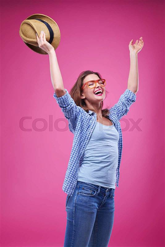 Mid shot of girl takes off the hat and rejoices in the studio. Female isolated over pink background in the studio , stock photo