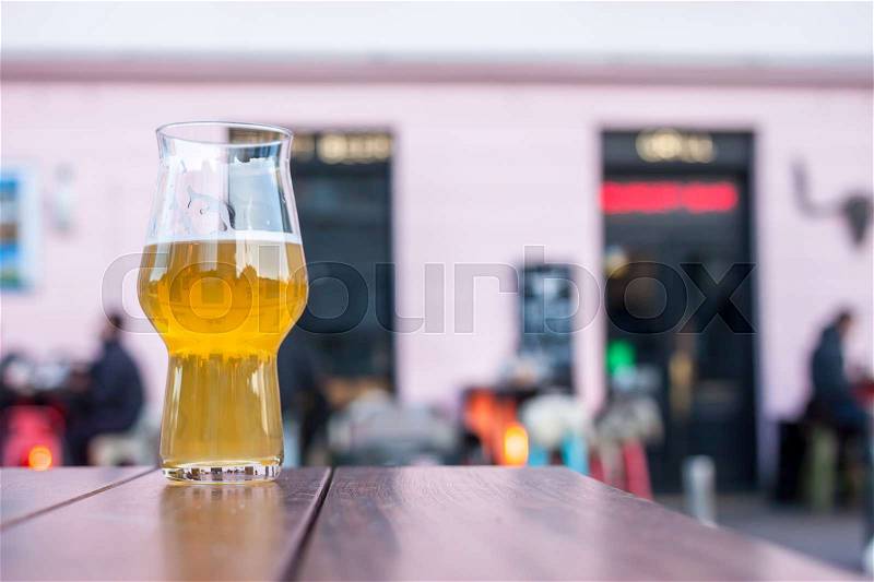 Glass of beer on table edge outside bar background, stock photo
