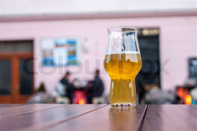 Glass of beer on table edge outside bar background, stock photo