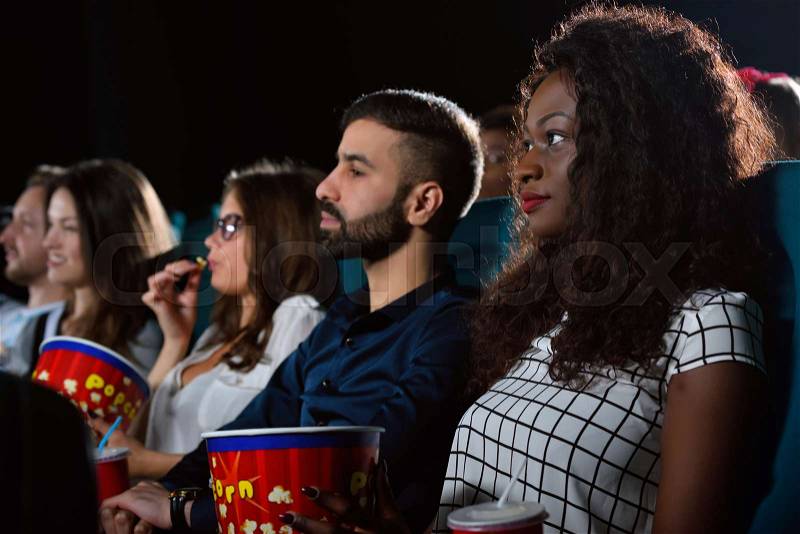 Friday nights. Group of multicultural friends enjoying a movie together at the cinema , stock photo