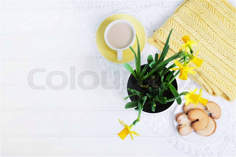 Indoor table setting. Narcissus flower in a pot with cookies and tea cup, stock photo