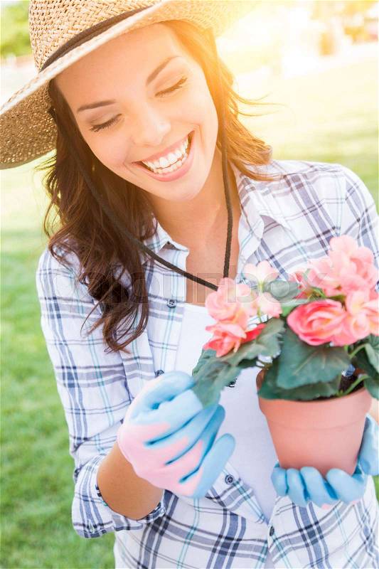 Happy Young Adult Woman Wearing Hat and Gloves Gardening Outdoors, stock photo