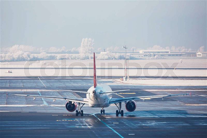 Airport in winter. Airplane is taxiing to the runway for take off, stock photo