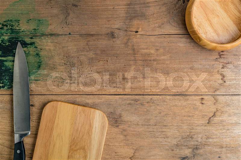 Kitchen knife with wooden cutting board and wooden bowl on brown wooden desk, stock photo