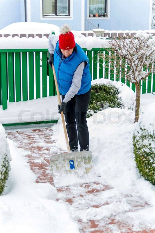 A woman shoveling the new snow from a path. onset of winter, stock photo